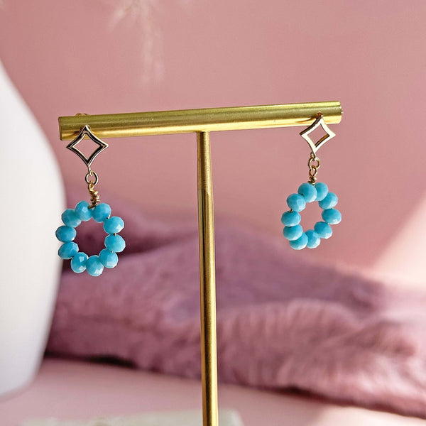 Image shows Beaded Turquoise Circle Drop Earrings hanging on a gold earring stand