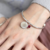 Image shows model wearing Child's Personalised Disc Birthstone Bangle with the name Elliotte engraved and July birthstone
