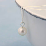 close up of an ivory pearl hanging off a silver chain