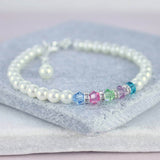 Family birthstone pearl bracelet lying on grey stone coaster