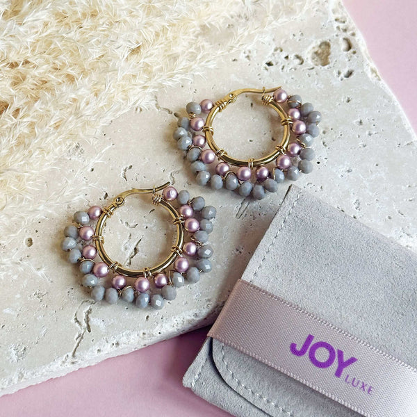 Image shows Mauve and Grey Beaded Crystal Hoops lying on a stone slab