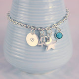  Image shows milestone birthday personalised charm bracelet with initial disc B, number 40, star charm and Blue zircon birthstone