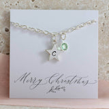 Image shows personalised star charm bracelet with a star engraved with the letter C and August birthstone on a Merry Christmas sentiment card