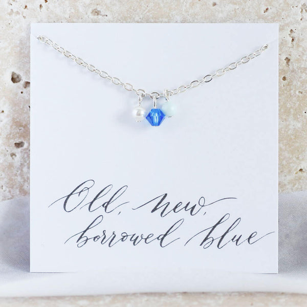 Image shows silver plated something blue chain anklet with three charms from left to right - pale blue pearl, Swarovski crystal bead and ivory dainty pearl. Anklet is mounted on an 'old, new, borrowed, blue' sentiment card,