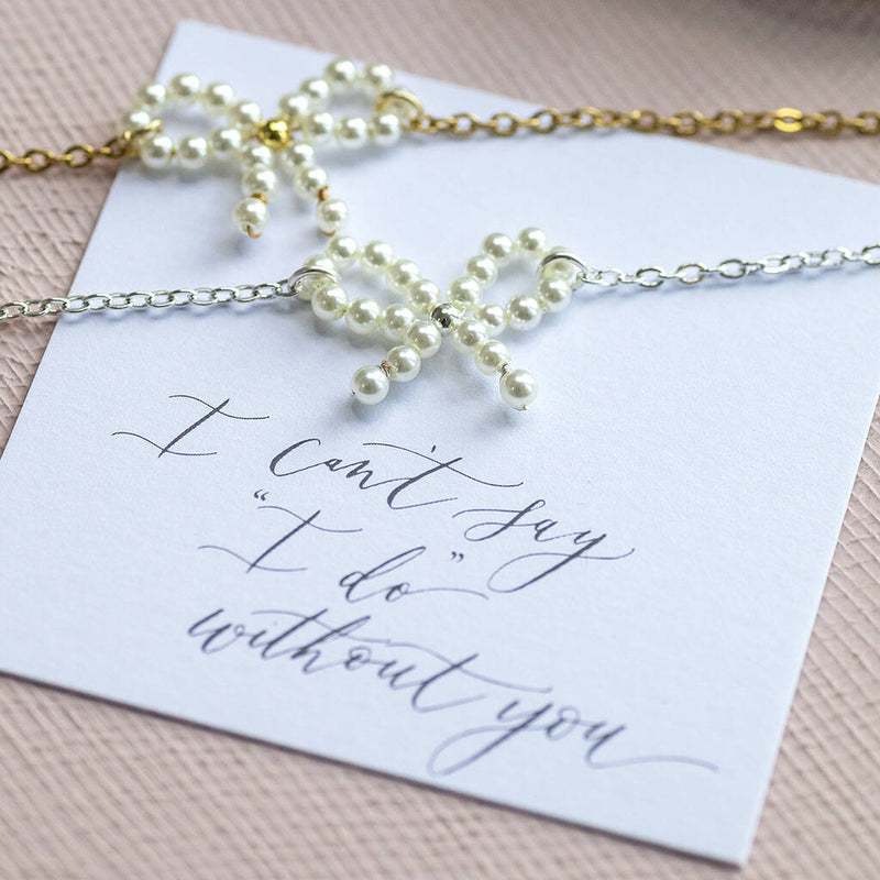 Image shows gold and silver plated Bridesmaid Pearl Bow Bracelets on an "I can't say 'I do' without you" sentiment card. 