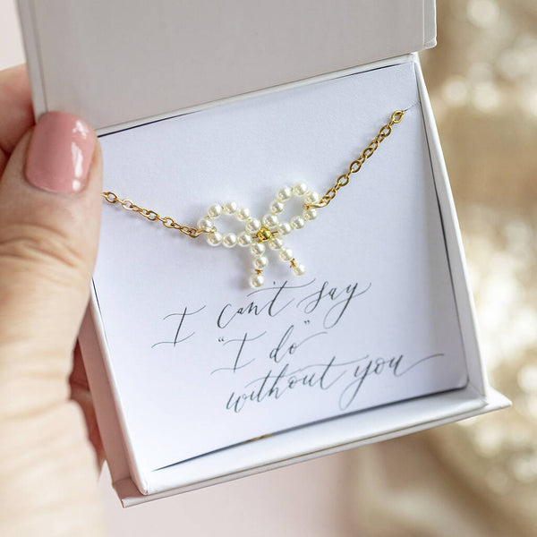 Image shows gold plated Bridesmaid Pearl Bow Bracelet on an "I can't say 'I do' without you" sentiment card in a JOY by Corrine Smith gift box.