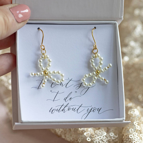 Image shows gold plated Bridesmaid Pearl Bow Earrings on an "I can't say 'I do' without you" sentiment card in a JOY by Corrine Smith gift box.