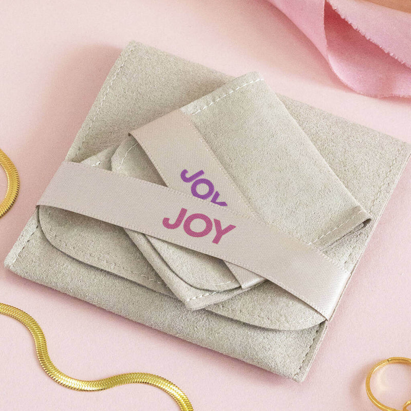 Image shows JOY suedette pouch in two sizes on a pink backdrop.