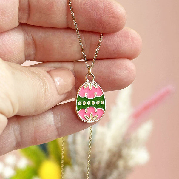 Pink and green enamel Easter egg charm gold plated necklace displayed on a persons hand