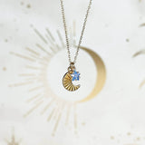 Image shows Moon and Birthstone Star Charm Necklace with blue September birthstone in front of a white backdrop