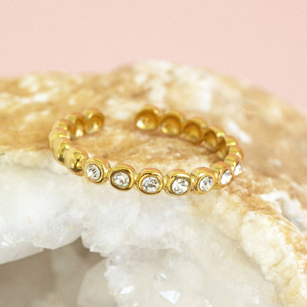 Image shows crystal band ring on a pink backdrop.