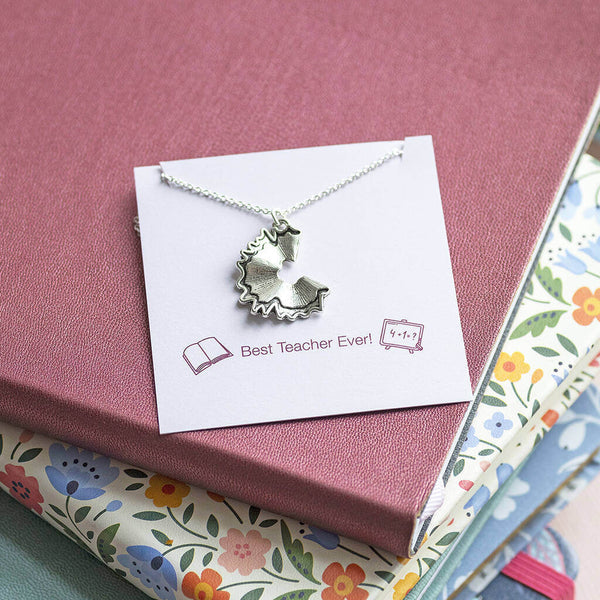 A silver plated necklace with a pencil shaving charm displayed on a Best Teacher Ever sentiment card.