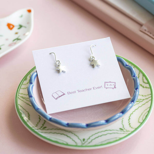 Silver star earrings presented on Best Teacher Ever! sentiment card sitting on top of two jewellery trinket plates.