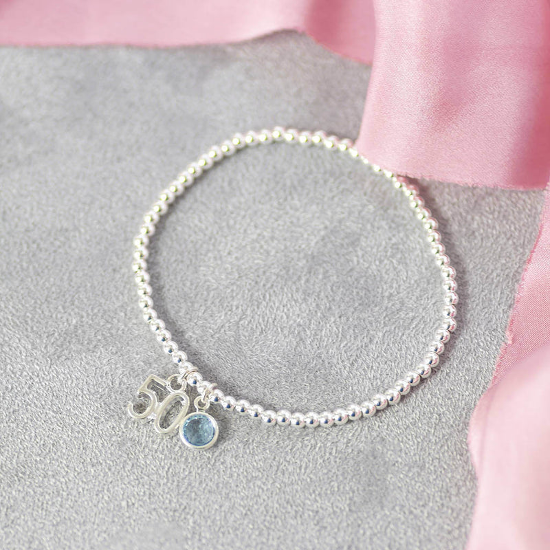 image shows silver plated 50th birthday birthstone charm bracelet with '50' charm and Swarovski birthstone crystal