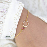 Model wears minimalist gold circle birthstone bracelet with October Rose Swarovski Birthstone.