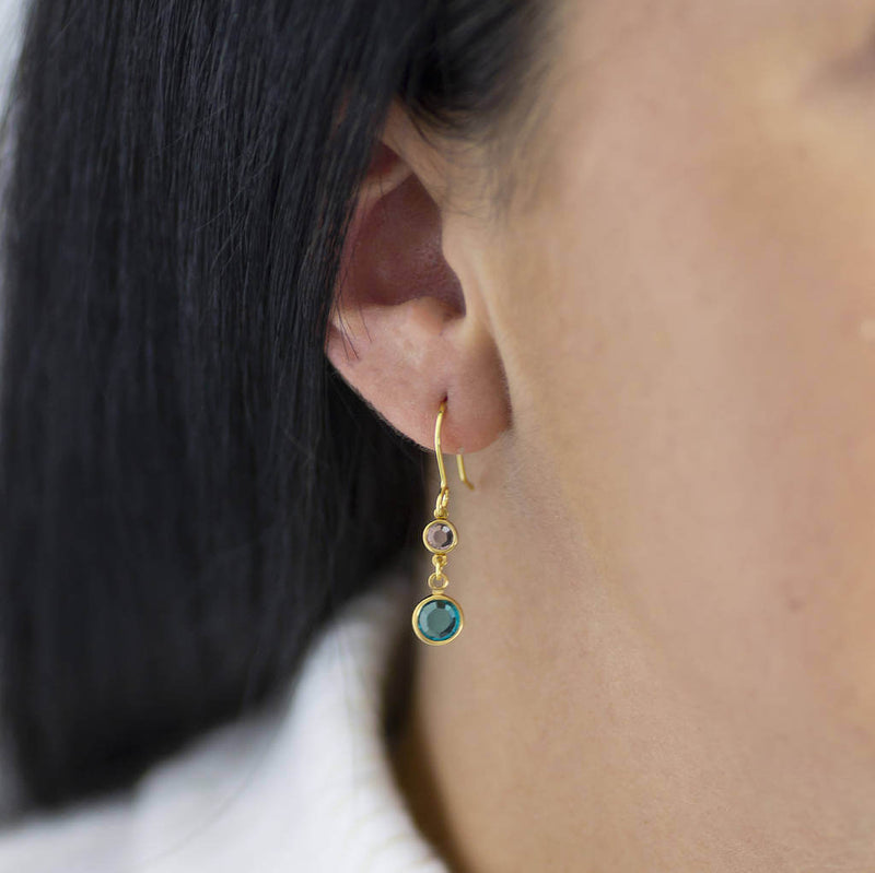 Model wears gold plated Mother and Child Birthstone Earrings with April crystal to represent child and December Blue Zircon to represent mother. Available in sterling silver.