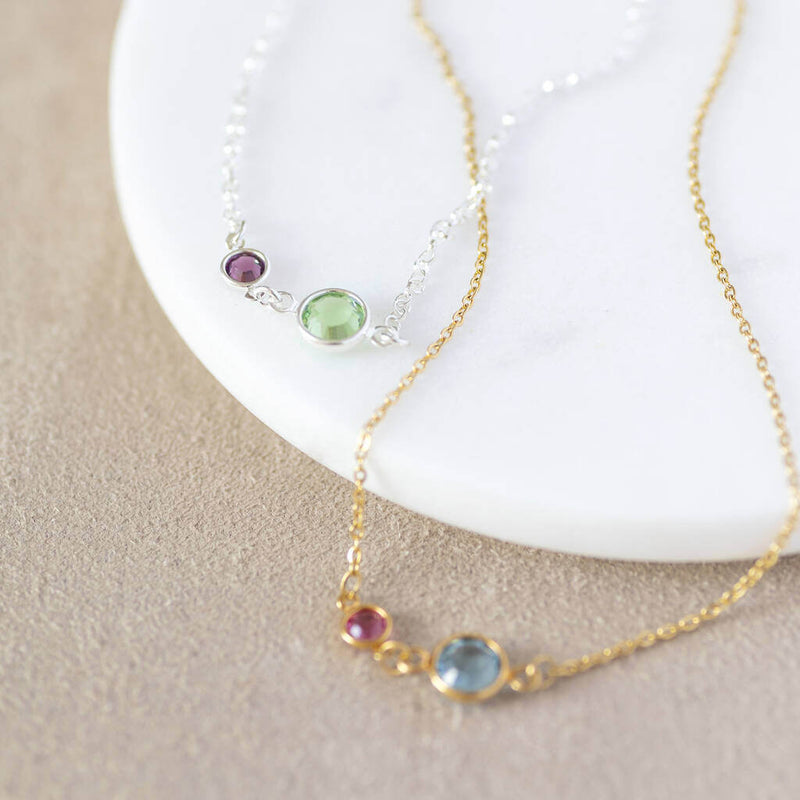 Images shows two mother and child birthstone link necklaces. Sterling silver chain with February Amethyst and August Peridot and gold plated chain with February amethyst and March aquamarine. Sitting on a white backdrop.
