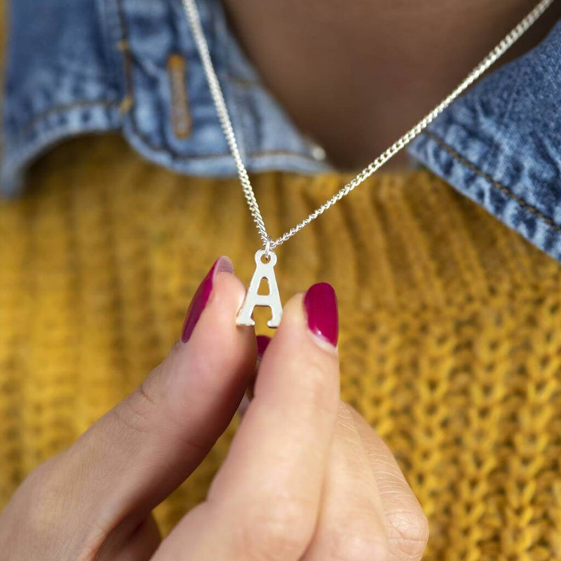 model wears silver plated initial alphabet charm necklace with the letter 'A'.