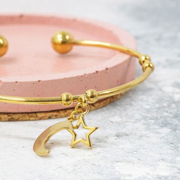 image shows gold plated heavenly bangle with crescent moon and star charms.