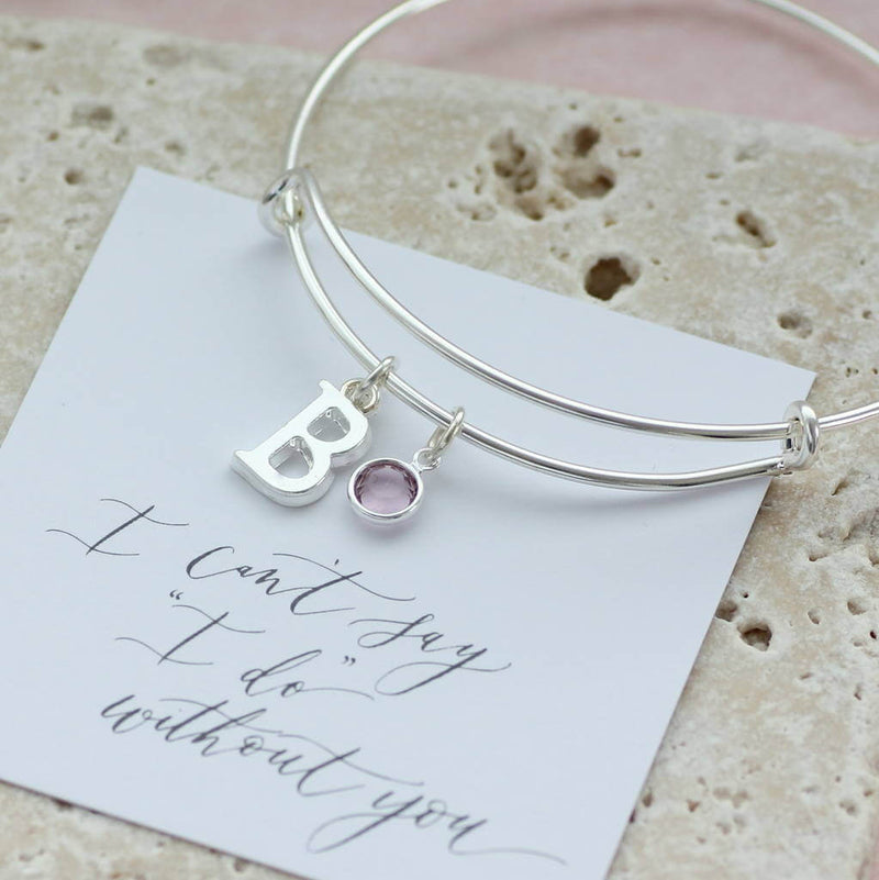 Image shows personalised initial birthstone bangle with initial 'B' and a Swarovski birthstone charm on a sentiment card that reads 'I can't say "I do" without you'