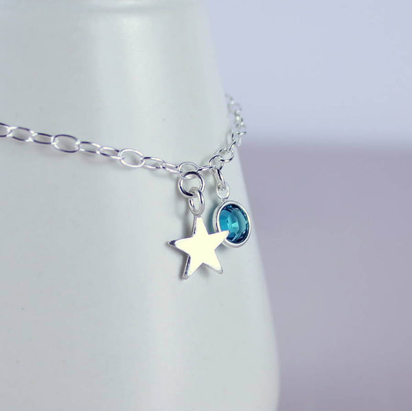 Image shows Sterling silver initial star birthstone bracelet with December blue zircon Swarovski crystal charm, and sterling silver star charm.
