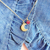 image shows a woman in a denim top wearing a gold moon necklace with birthstone charm detail