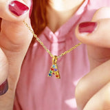 Image shows a woman in a pink top holding a gold initial A necklace that is set with rainbow coloured gemstones