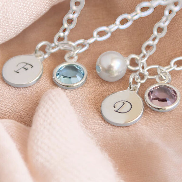 image shows two silver personalised charm bracelets with handstamped nitials and birthstone charms