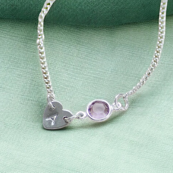 image shows a silver heart bracelet with initial A and June birthstone detail on a green background