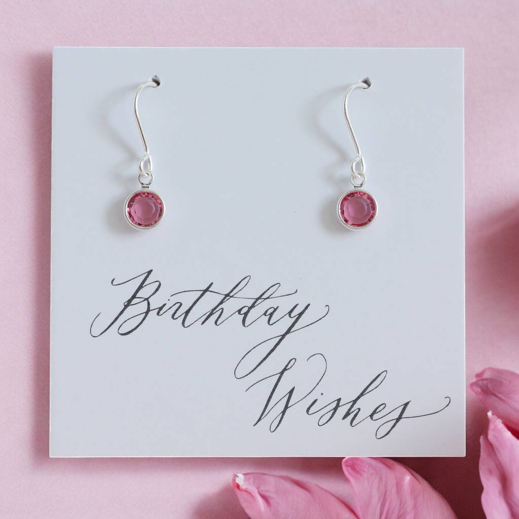 Image shows a pair of silver october birthstone earrings on a card that reads birthday wishes