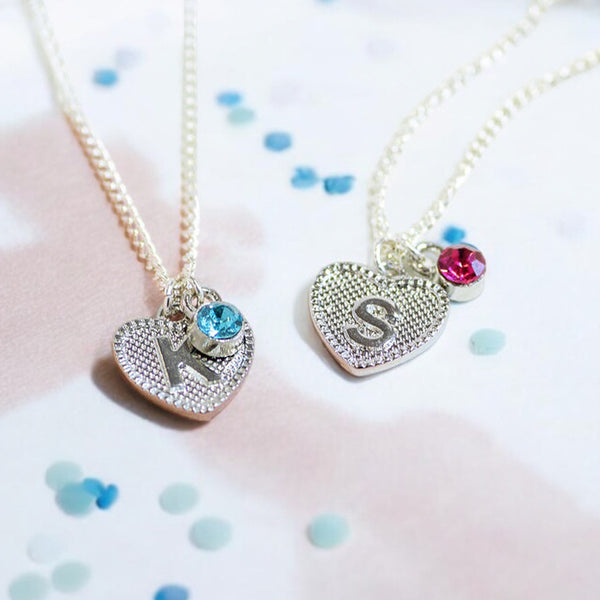 image shows two children's heart necklaces with initials K and S and birthstones for December and October on a pastel confetti scattered background