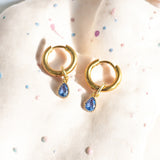 image shows a pair of gold plated hoop earrings with teardrop birthstone detail for December birthdays