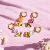 Image shows a selection of glass tulip earrings in orange, pink, blue and lilac against a dusky pink fabric bacground