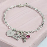 Image shows a silver personalised 21st birthday charm bracelet on a pink backgroundbi