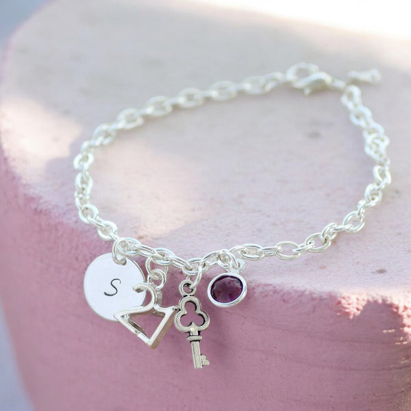 Image shows a silver personalised 21st birthday charm bracelet on a pink backgroundbi