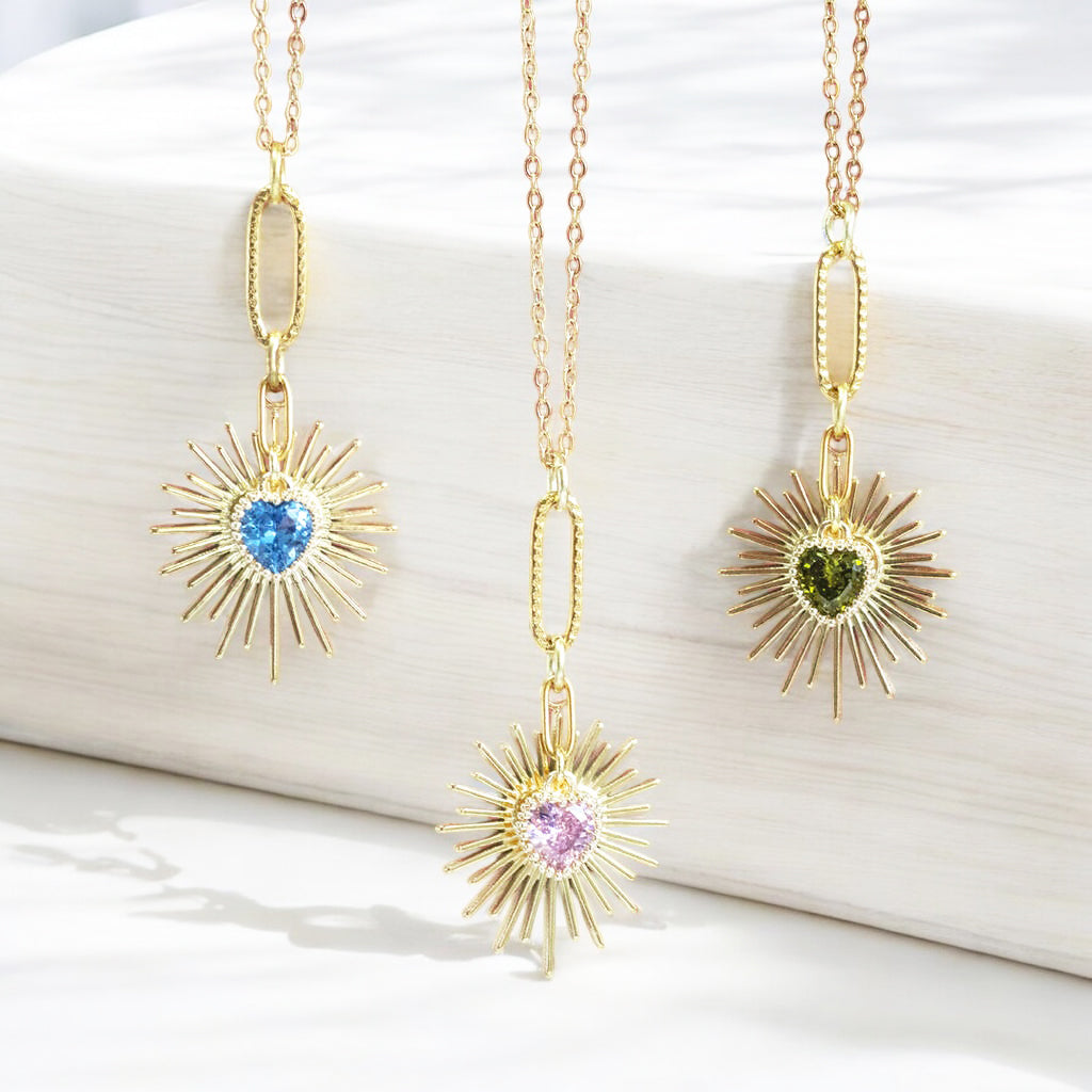 image shows three gold heart necklaces with birthstone charm detail on a white background