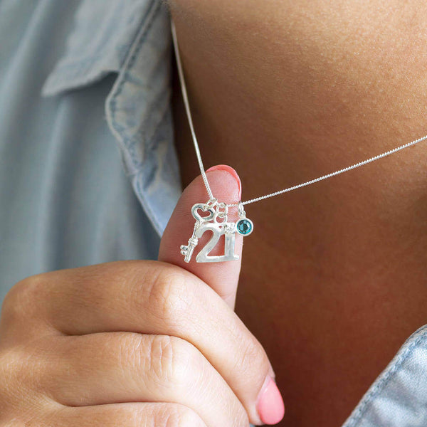 Image shows model pushing a 21st birthday sterling silver charm necklace out with her thumb