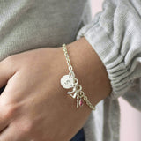 Image shows model wearing 21st birthday personalised charm bracelet with initial disc S and Rose birthstone