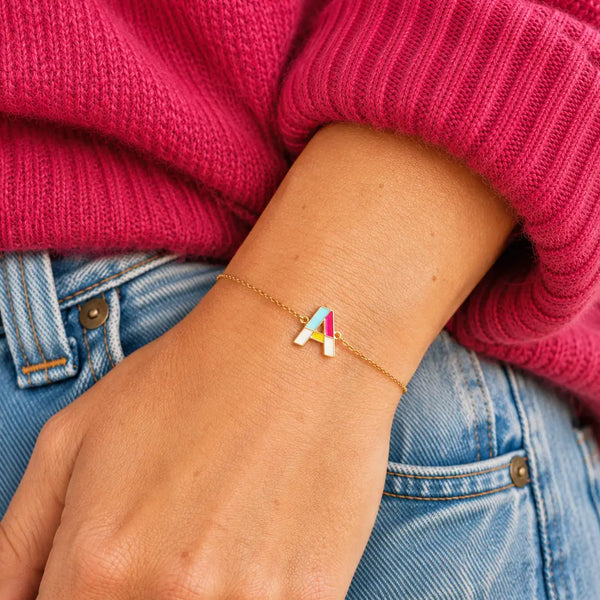 Personalised gold plated enamel initial bracelet with colourful A letter charm worn on the wrist