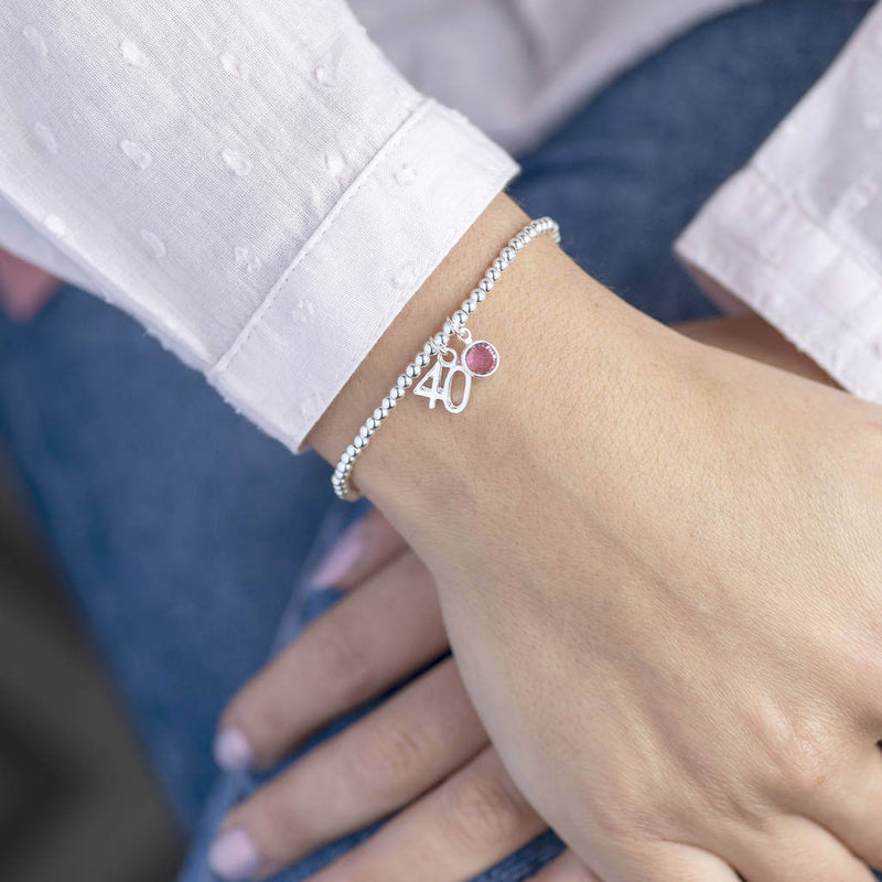 Image shows model wearing 40th birthday beaded birthstone charm bracelet with rose birthstone