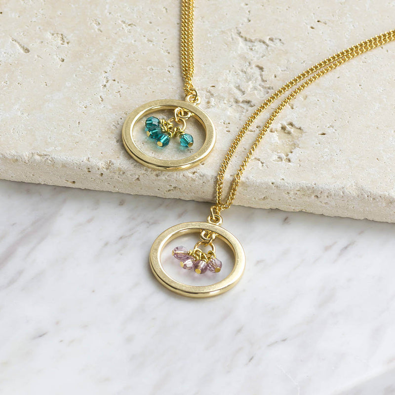 Image shows two 40th birthday gold circle birthstone necklaces