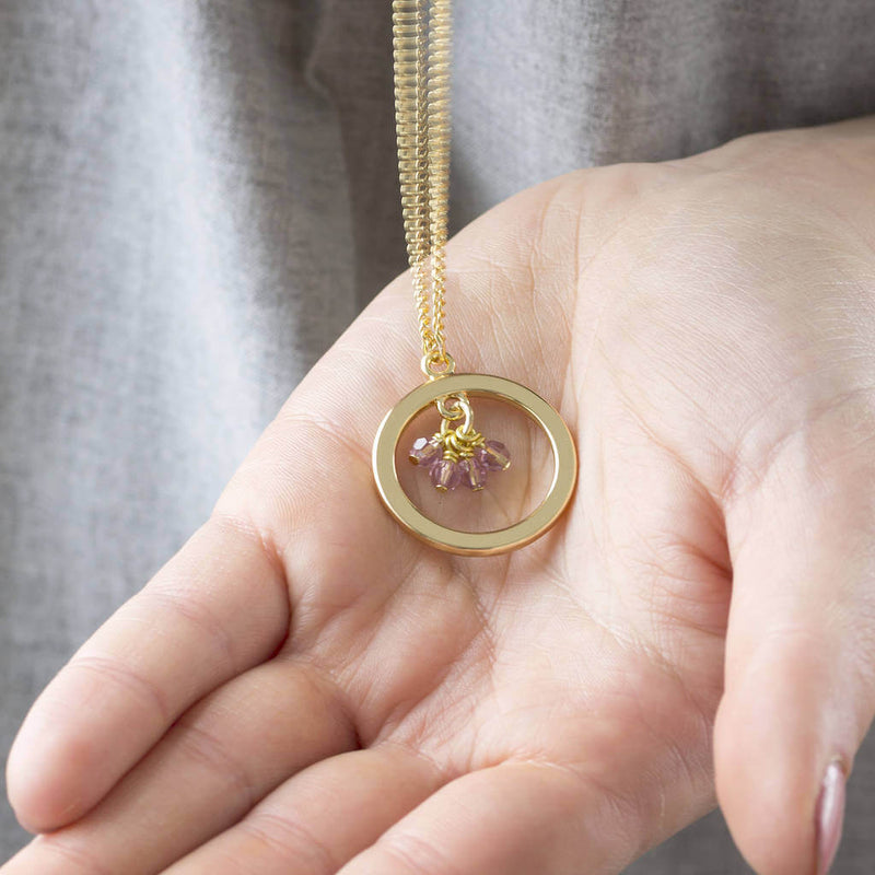 Image shows model holding 40th birthday gold circle birthstone necklace with Light amethystbirthstone