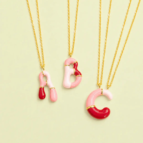 Pink enamel personalised initial necklaces with A B and C letter pendants on gold chains