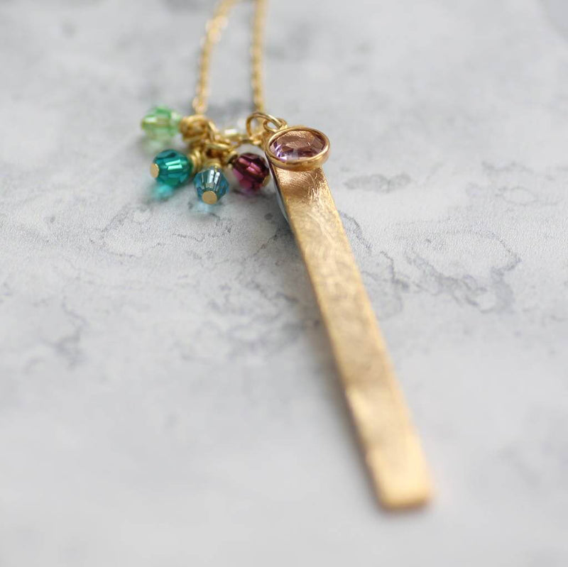 Image shows gold plated long length family birthstone necklace with a large amethyst birthstone and four small birthstone beads.