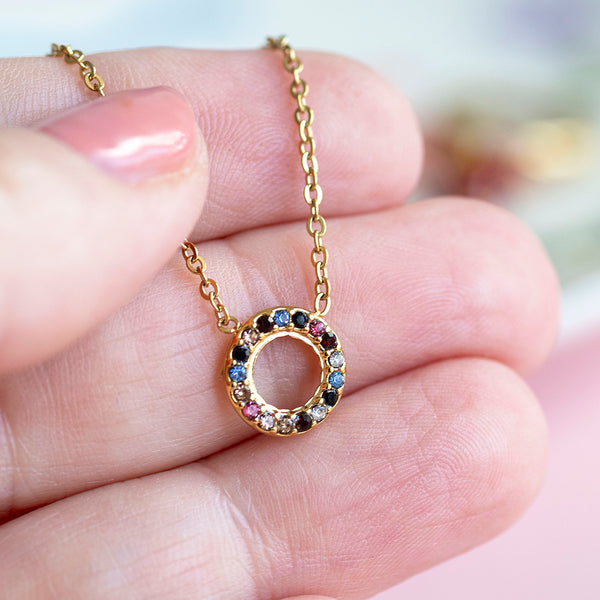 Images show a hand holding a gold multi coloured gemstone eternity circle necklace