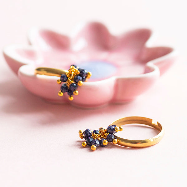 Image shows two gold plated adjustable ring with blue sandstone charm detail on a pink background