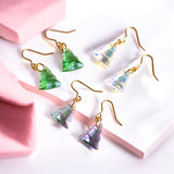 image shows three pairs of christmas tree earrings on a pink and white background