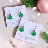 image shows glass Christmas tree earrings on white card that read merry Christmas