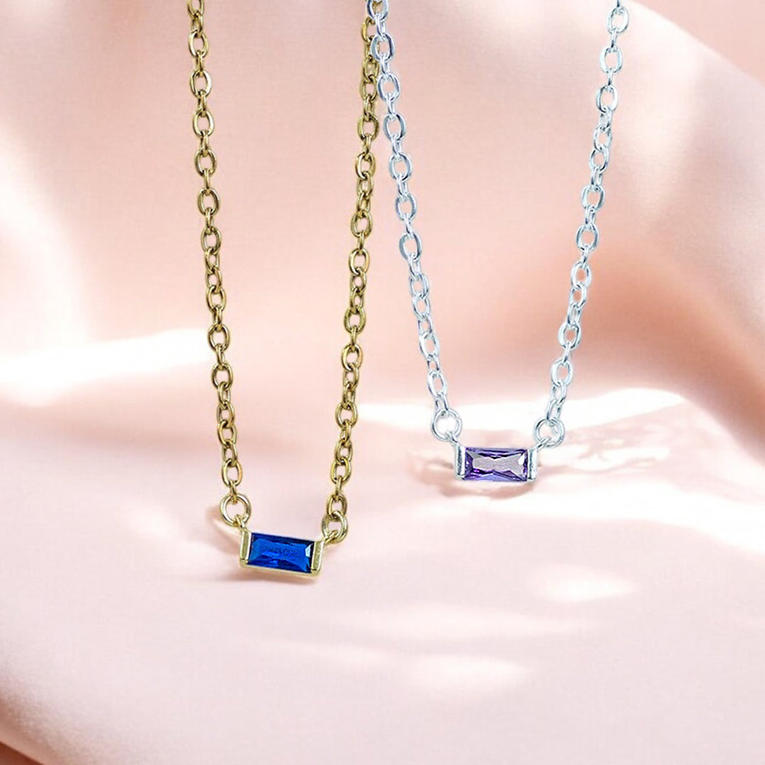 image shows a gold baguette birthstone necklace with sapphire stone and silver with amethyst stone