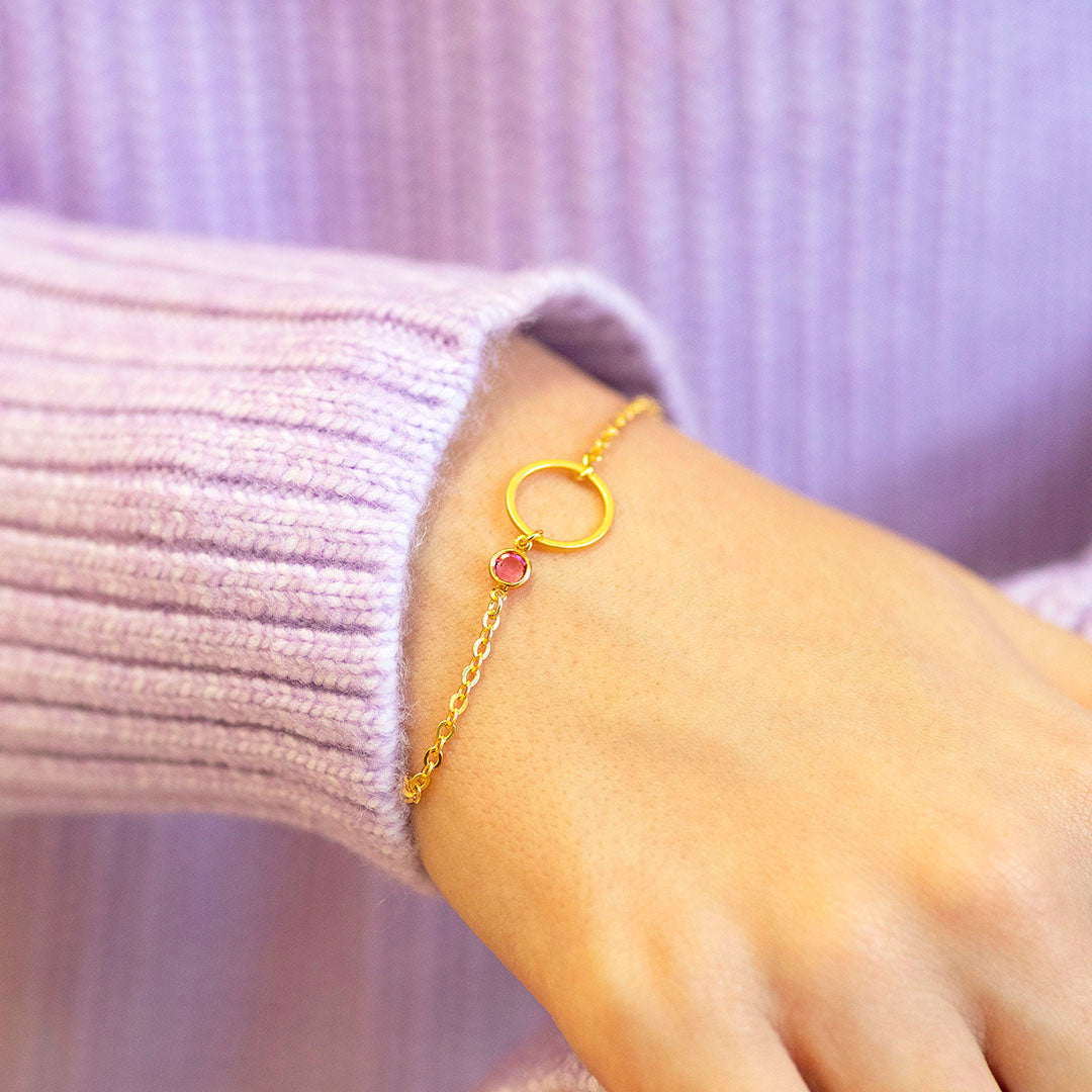 Gold plated Mother and Child Circle Birthstone Bracelet with rose birthstone, styled with a soft pink ribbed jumper.